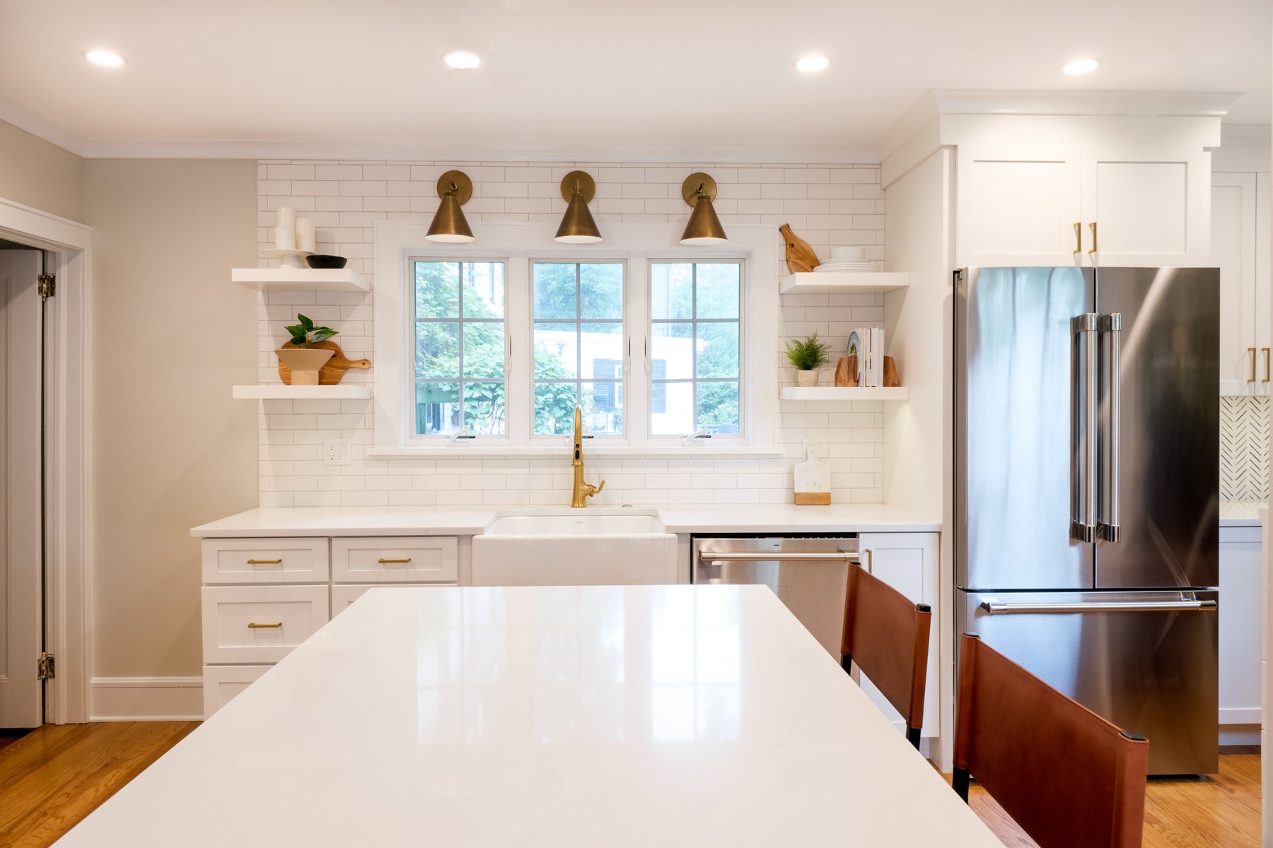 Bright family kitchen with a navy island, white cabinetry and warm brass details.