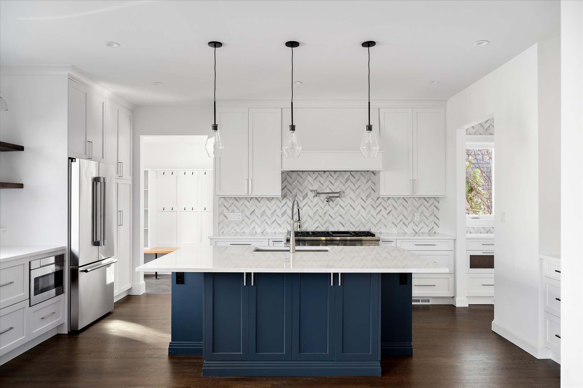 Wide view of the completed white kitchen and navy island.
