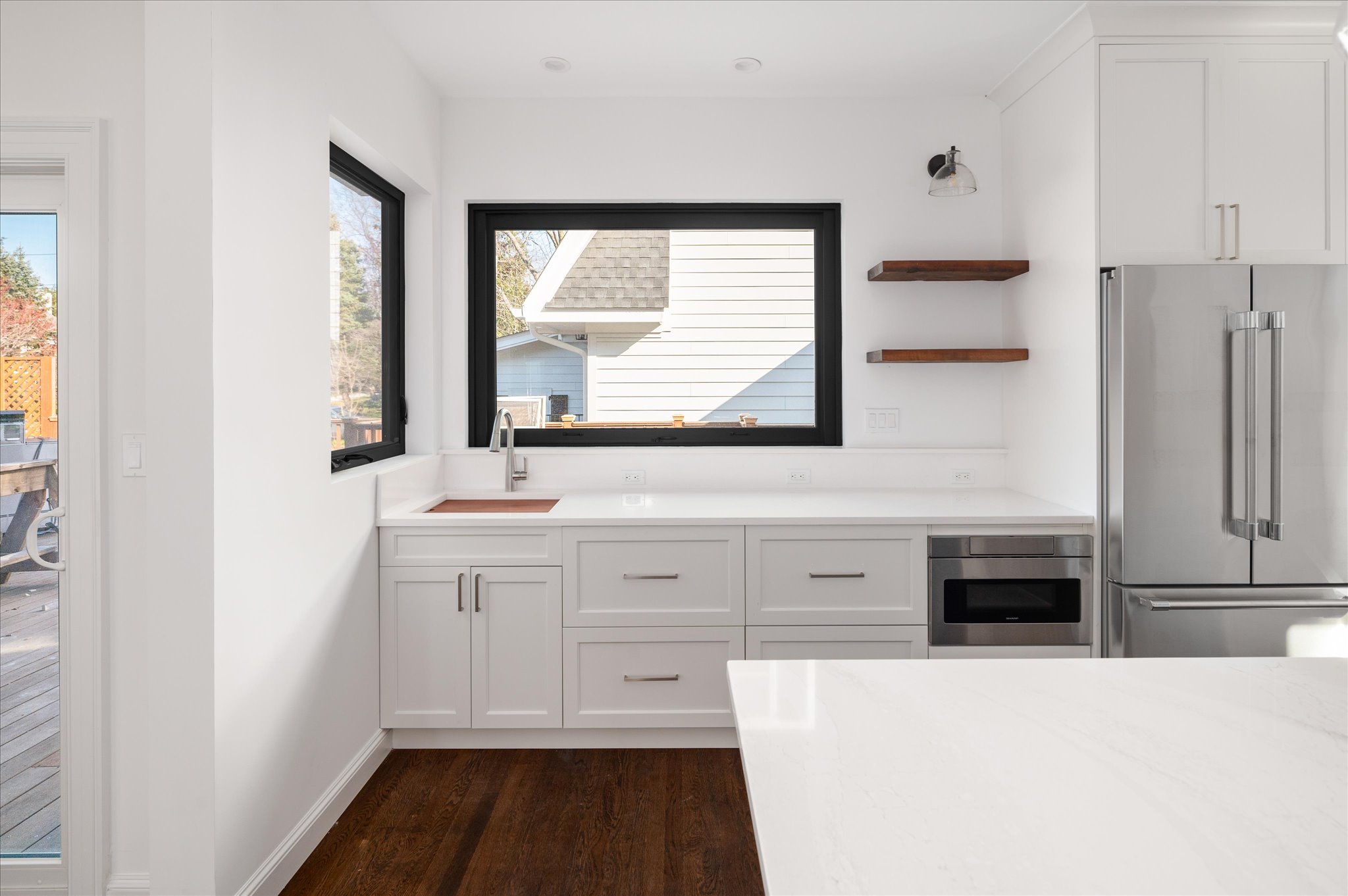 Tailored cabinetry below a black-framed kitchen window.